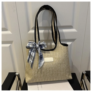 Detail of woven straw tote with black handles and a decorative Paris silk scarf