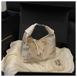 Detail of beige Chinese style handbag with floral embroidery and gold handle in gift box