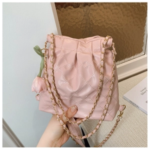 Detailed shot of pink quilted bucket bag featuring golden chain and tulip charm detail