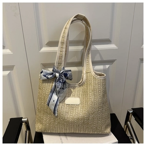 Detail of woven straw bucket bag featuring a decorative blue silk scarf and leather trim