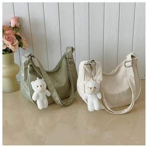 Detailed texture of dumpling shoulder bags in mint green and cream with plush bear charms
