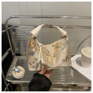 Detail of vintage beige floral jacquard embroidery bag with bird patterns and woven knot