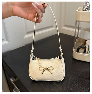 Détail d'un sac à main blanc cassé avec cuir texturé lychee et nœud en métal doré
