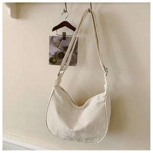 Detail view of cream-white hobo bag with textured fabric hanging on a wall