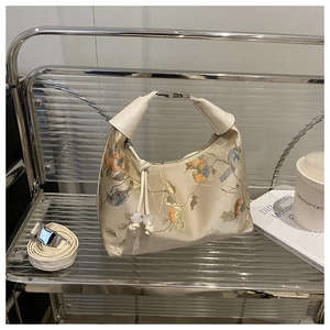 Detailed embroidery of birds and flowers on a cream satin oriental style handbag