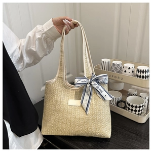 Detail of beige woven straw tote bag with elegant blue floral silk scarf handle decoration