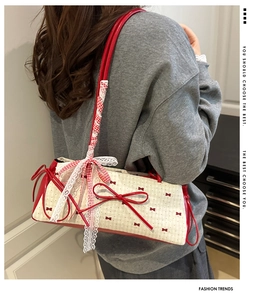 Detail showing the red bow shoulder strap with lace and ribbon wrap on the white handbag