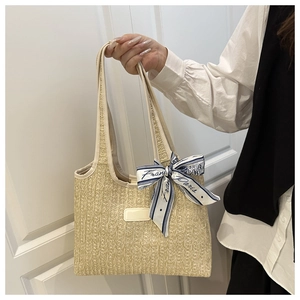 Close-up of beige woven tote bag featuring a blue France Paris silk scarf on handle