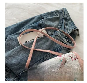 Détail de la bandoulière rose réglable et motif cartoon mignon sur le rabat du sac