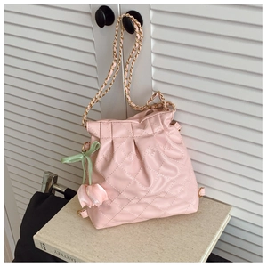 Detail of pink quilted bucket bag featuring a tulip charm and gold chain strap