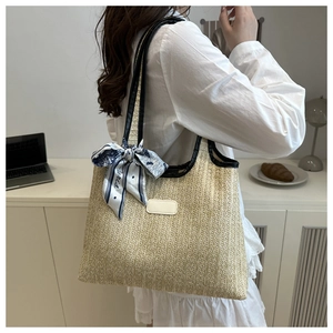 Detail of woven straw tote bag with black leather trim and decorative Paris silk scarf