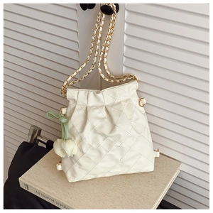 Close-up of cream quilted bucket bag with gold chain strap and tulip charm detail