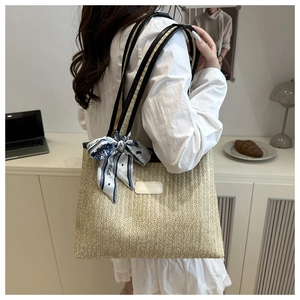 Detail view of woven straw tote bag with printed silk scarf and black leather straps