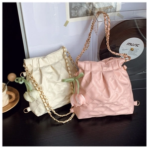 Detail of quilted bucket bags in cream and pink with chain straps and tulip charms