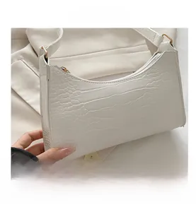 Close-up of white crocodile embossed texture on a sleek underarm bag with metal buckle