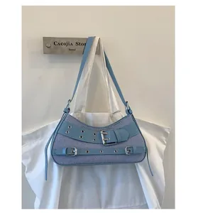 Detail of Y2K denim and leather shoulder bag featuring silver metal eyelets and buckles