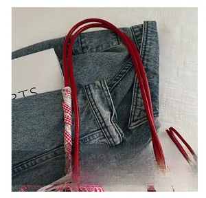 Close-up of red handle with ribbon detail on cream polka dot bow print handbag