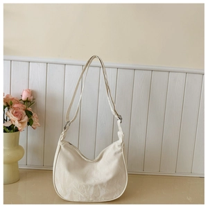 Close-up of cream-white hobo bag showing natural leather texture and metal strap buckle