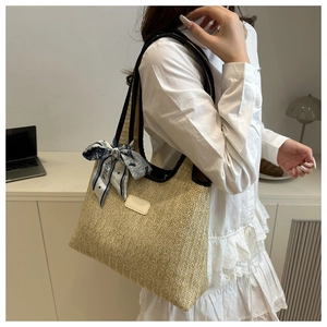 Detail of woven straw bucket bag featuring a decorative Paris print silk scarf accessory