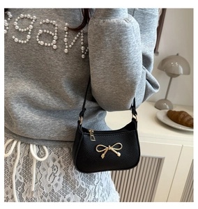 Détail d'un sac sous les aisselles en cuir grainé noir avec boucle dorée sur un mannequin