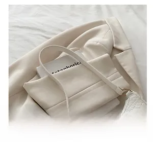 Close-up of white croc-embossed underarm bag detail with metallic silver link and strap