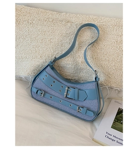 Detail of light blue Y2K denim and leather shoulder bag with metal buckle straps