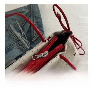 Detail of smooth red zipper and sweet bow print on off-white canvas shoulder bag