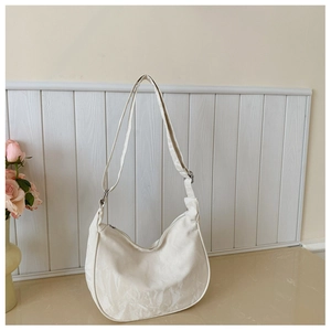 Detail of white dumpling bag showing unique wrinkled texture and metallic zipper