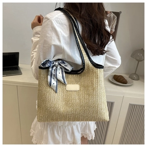 Detail of woven straw bucket bag with black leather trim and silk scarf for commute