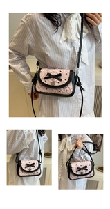 Détail du sac bandoulière rose en jacquard avec nœud noir et pendentif cœur