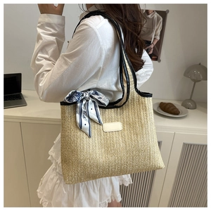Detail of woven straw tote bag with black leather trim and vintage patterned silk scarf decor