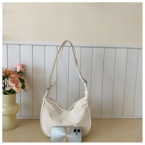 Close-up of cream crescent bag with marble texture and smartphone for size reference