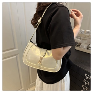 Detail einer cremeweißen Lackleder-Schultertasche mit eleganter goldener Metallschnalle