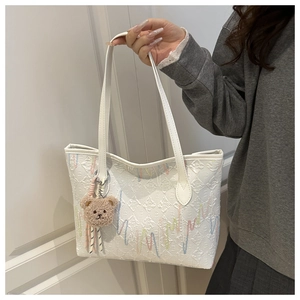 Detailed texture of white tote bag with rainbow embroidery and cute bear charm pendant