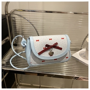 Détail du sac bandoulière à carreaux bleu clair avec nœuds rouges et pendentif cœur