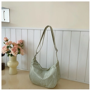 Detail showing light green wrinkled texture and adjustable strap on a crossbody bag