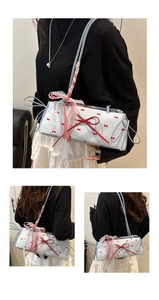 Detail of light blue bow handbag featuring red polka dots and lace ribbon shoulder strap