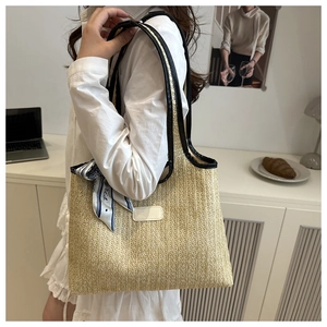 Detail of woven straw tote bag with black leather strap and striped Paris silk scarf