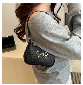 Detail of lychee pattern leather underarm bag with gold bow knot and slim shoulder strap