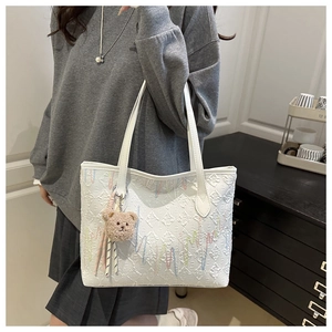 Detail of white tote bag with embossed floral texture and colorful embroidery accents