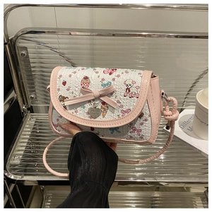Détail du nœud rose et du pendentif cœur sur le sac bandoulière imprimé papillon
