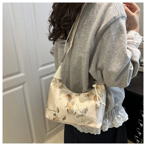 Detailed close-up of floral bird embroidery and bead tassels on silk hobo bag