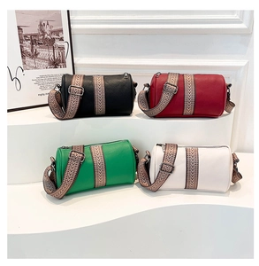 Row of leather barrel bags with ethnic woven straps on white display stands