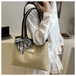 Detail of straw woven tote bag featuring a decorative Paris print scarf on the handle