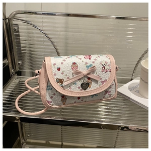 Détail d'un sac à bandoulière rose avec motifs cartoon et pendentif cœur en métal