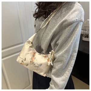 Detail of silk satin half-moon bag featuring elegant floral embroidery and bead drawstring