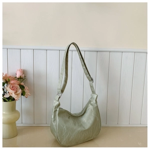 Detail of light green crescent bag showing textured finish and wide shoulder strap