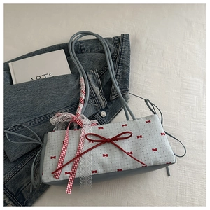 Détail du sac à bandoulière en dentelle bleue avec motifs de nœuds rouges