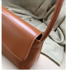 Détail d'un sac à bandoulière en cuir caramel avec coutures fines et poignée ronde