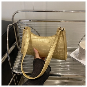 Close-up of golden faux crocodile skin texture and zipper on retro underarm shoulder bag